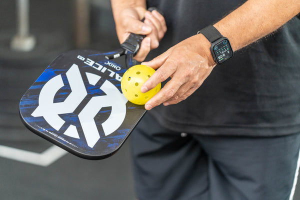 pickleball player holding onix malice pickleball paddle and dura fast 40 ball