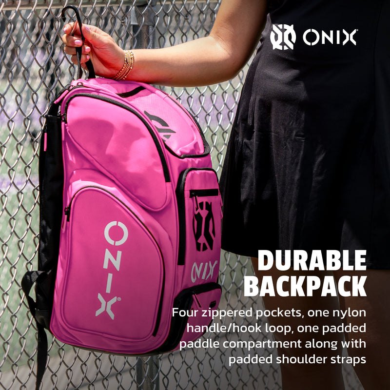 Pink Onix backpack held by a person against a chain-link fence.
