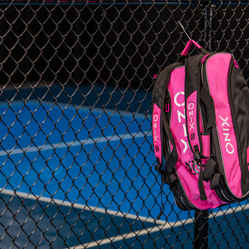 ONIX Pink Pickleball Backpack Hanging on fence